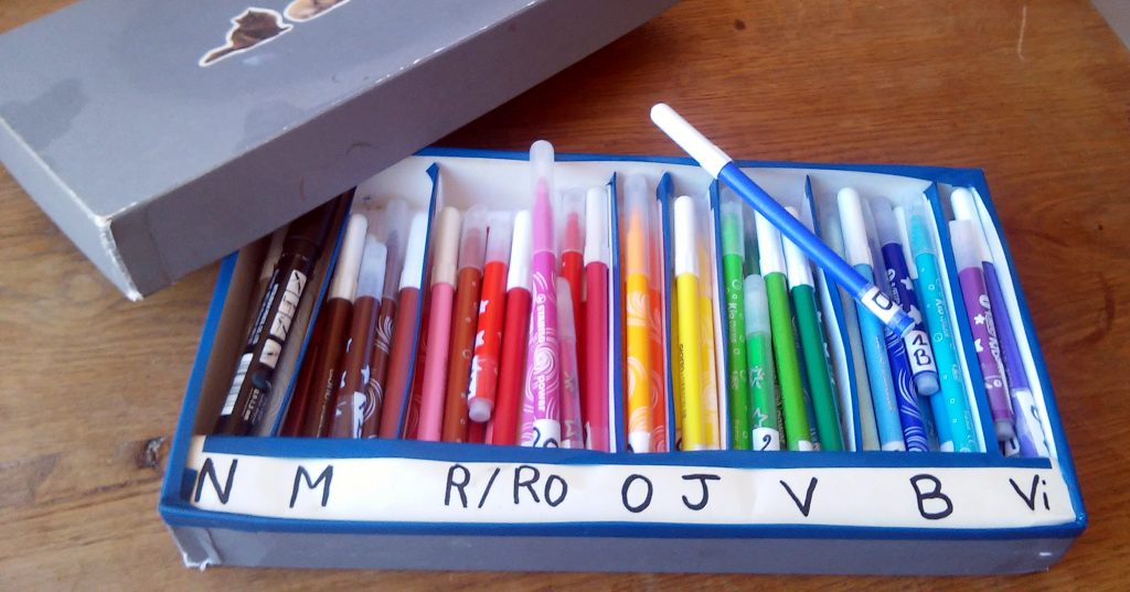 feutres rangés par couleur dans une boîte à compartiment
